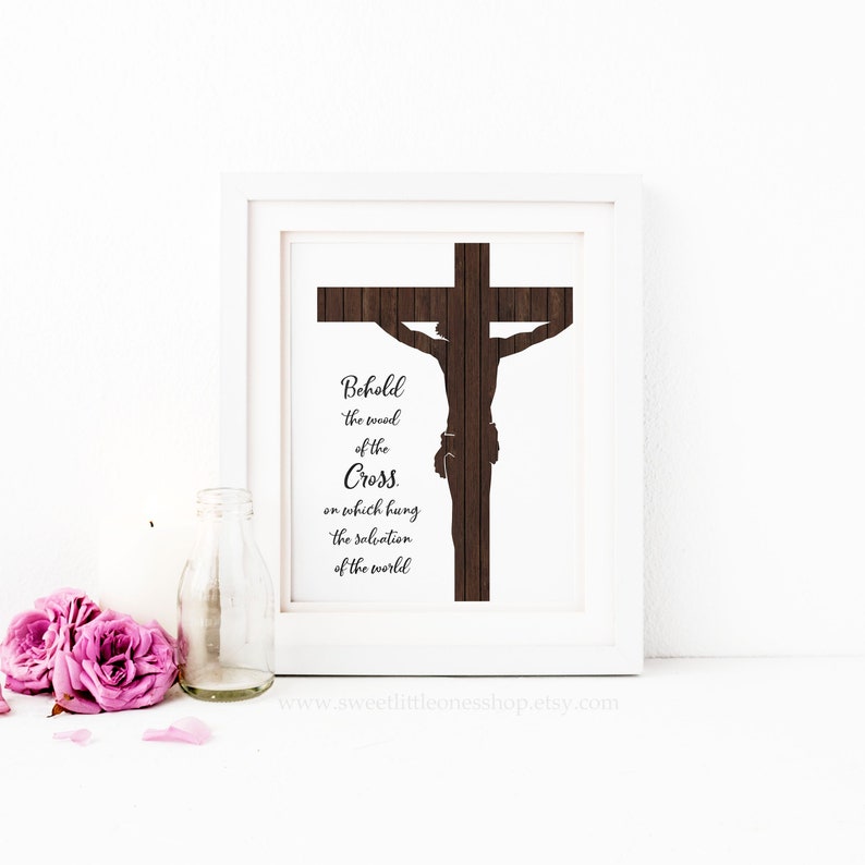 May include: A framed print with a woodgrain background featuring a silhouette of a cross with the text "Behold the wood of the Cross. on which hung the salvation of the world".