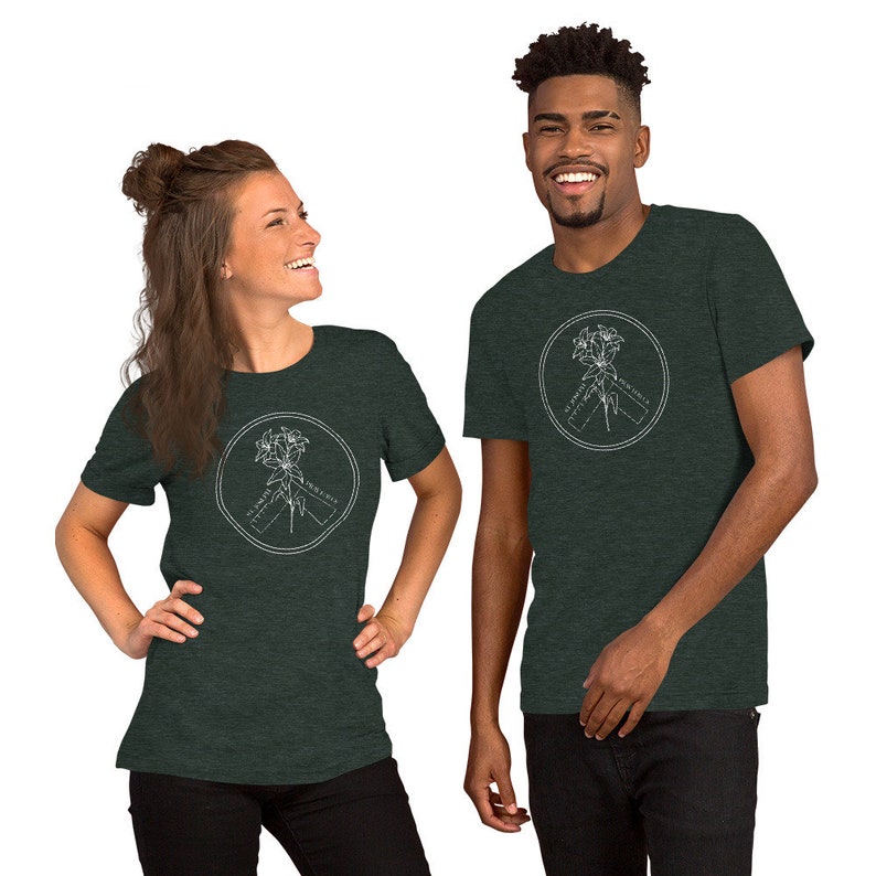 May include: Two people wearing dark green t-shirts. Each shirt features a white circular design with a floral illustration and the text "ST JAMES PENINSULA". The shirts are made of a soft material.