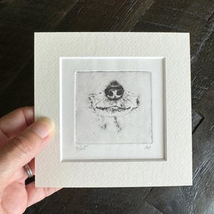 May include: A small, square, black and white print of a dog's nose and mouth, framed in a white mount. The print is numbered 4/25 and signed. The artwork is a detailed etching, showcasing the dog's features.