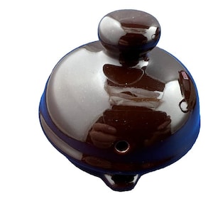 Puede incluir: Una tapa de tetera de cer&aacute;mica marr&oacute;n oscuro con un acabado brillante. La tapa tiene una parte superior redondeada con un peque&ntilde;o pomo y un pico curvo. La tapa est&aacute; dise&ntilde;ada para una tetera.