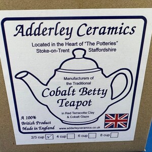 May include: A label on a cardboard box features the text "Adderley Ceramics" and a drawing of a teapot. The label states the teapot is the "Cobalt Betty Teapot" made in England. The label also includes the British flag.
