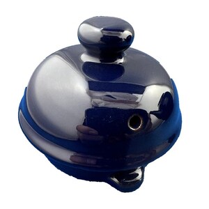 May include: A shiny, navy blue teapot lid with a silver-colored, reflective surface. The lid has a small, rounded handle on top and a blue band around the base. The design is simple and elegant.