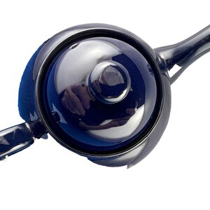 May include: A dark blue ceramic teapot with a matching lid and handle. The teapot has a glossy finish and a classic design, suitable for brewing tea. The spout and handle are curved, and the lid has a small knob for easy removal.