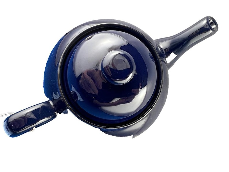 May include: A dark blue ceramic teapot with a matching lid and handle. The teapot has a glossy finish and a classic design, suitable for brewing tea. The spout and handle are curved, and the lid has a small knob for easy removal.
