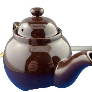Puede incluir: Una tetera de cer&aacute;mica marr&oacute;n con cuerpo redondeado, boquilla curva y tapa con peque&ntilde;o pomo. La tetera tiene un acabado brillante y est&aacute; dise&ntilde;ada para preparar t&eacute;. Es un dise&ntilde;o cl&aacute;sico.