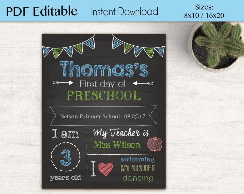 Op de afbeelding: Een afdrukbaar bord in krijtbord-stijl voor de eerste schooldag van een kind. Het bord is versierd met groene en blauwe vlaggetjes en heeft de naam "Thomas's" in blauwe tekst. Het bord bevat ook de tekst "First day of PRESCHOOL", "Nelson Primary School - 09.05.17", "I am 3 years old", "My Teacher is Miss Wilson", en "swimming I MY SISTER dancing".