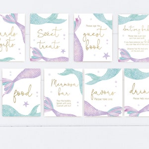 May include: Set of ten printable mermaid-themed signs for a baby shower. The signs feature a mermaid tail with purple and blue scales and gold lettering. The signs include: Cards and Gifts, Sweet Treats, Guest Book, Don't Say Baby, Food, Mimosa Bar, Favors, Drinks.