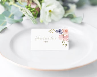 May include: A white place card with a floral design in shades of pink, purple, and green. The text "Your text here text" is printed in gold on the card.