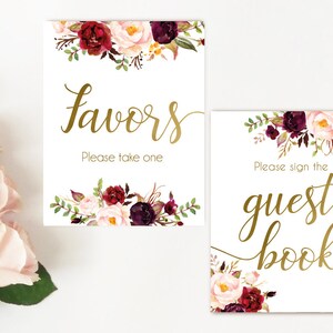 K&ouml;nnte beinhalten: Zwei druckbare Schilder mit burgunderroten und blushfarbenen Blumendesigns und goldener Kalligrafie. Das erste Schild lautet "Favors" und "Please take one". Das zweite Schild lautet "Please sign the guest book".