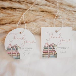 May include: Two round and square thank you tags featuring a stack of books with a pink ribbon and flowers. The text on the tags reads "Thank you" with a small heart and "For celebrating with me! Sarah".