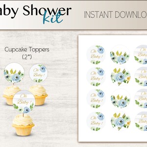 May include: A set of 12 blue and white cupcake toppers with gold lettering that says "Oh Baby!" The toppers are 2 inches in diameter and feature a watercolor floral design.