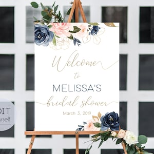 Può includere: Un cartello bianco su un cavalletto di legno con le parole "Welcome to Melissa's bridal shower" in oro. Il cartello è decorato con fiori ad acquerello blu navy, rosa cipria e oro. È inclusa anche la data 3 marzo 2019.