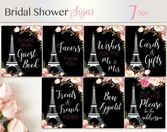 Könnte beinhalten: Sieben druckbare Schilder mit schwarzem Hintergrund, einer weißen Eiffelturm-Grafik und rosafarbenen floralen Akzenten. Die Schilder enthalten den Text: "Gästebuch", "Geschenke", "Wünsche für das Brautpaar", "Karten & Geschenke", "Leckereien & Französische Küsse", "Guten Appetit" und "Bitte die Adresse sein".