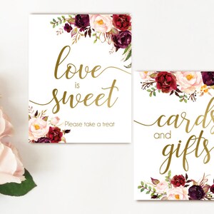 K&ouml;nnte beinhalten: Zwei druckbare Schilder mit einem Blumendesign in den Farben Burgunderrot, Rosa und Gr&uuml;n. Der Text auf den Schildern lautet "Liebe ist s&uuml;&szlig;, bitte nimm einen Leckerbissen" und "Karten und Geschenke".