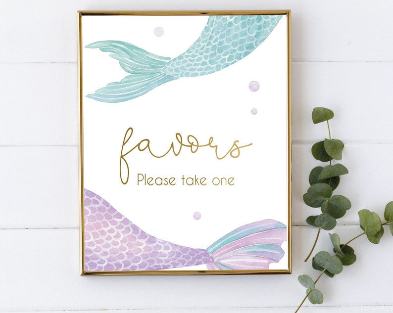 May include: A printable sign with a gold glitter font that says "favors" and "Please take one". The sign is decorated with two watercolor mermaid tails, one teal and one purple.