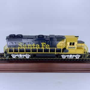 May include: A model train locomotive with a black and yellow color scheme. The words "Santa Fe" are printed in yellow on the side of the train. The number "3500" is printed in yellow on the side of the yellow cab.