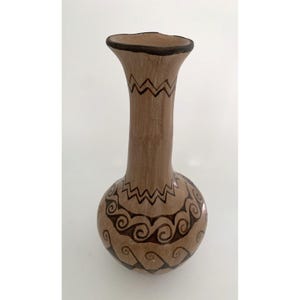May include: A brown ceramic vase with a bulbous base and a long, slender neck. The vase is adorned with dark brown geometric and swirl patterns. The rim is painted dark brown. The vase is approximately 8 inches tall.