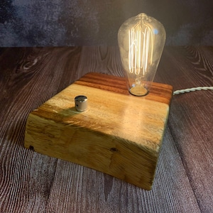 May include: A wooden lamp base with a light bulb and a switch. The base is made of reclaimed wood and has a natural finish.
