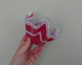 Könnte beinhalten: Eine rote und weiße Glasschüssel mit welligem Design. Die Schüssel ist aus klarem Glas mit einem roten und weißen Muster.