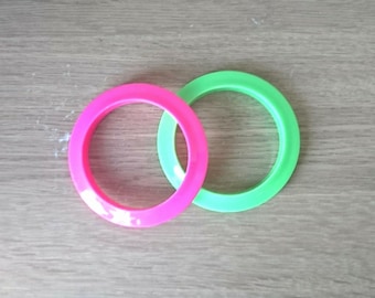 Può includere: Due anelli di plastica, uno verde e uno rosa. Gli anelli sono impilati uno sopra l'altro.