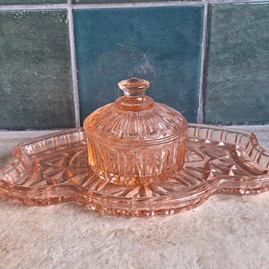 Vintage rosa sminkbord i glas, prydnadsskål och kruka med lock, sminkbricka i pressat glas, förvaring i art déco-stil