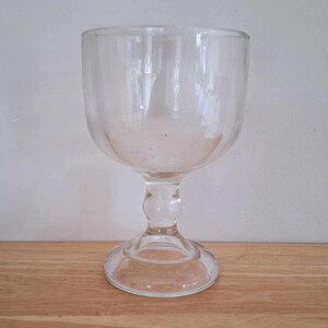 May include: A clear glass goblet with a wide bowl and a tall, slender stem. The goblet has a round base.