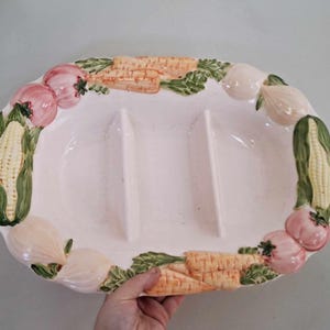 May include: White ceramic serving dish with three divided sections. The dish is decorated with a colorful vegetable design, including corn, carrots, onions, and tomatoes.