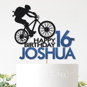 May include: A blue and black cake topper with a silhouette of a person riding a bicycle. The topper says "Happy Birthday Joshua 16th".
