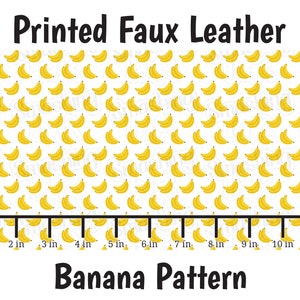 May include: Printed faux leather fabric with a repeating banana pattern. The fabric is white with yellow bananas. The fabric is 11 inches wide.