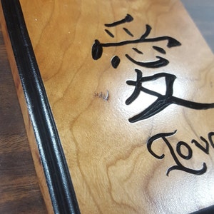 May include: A wooden sign with a black border. The sign has the words "Hope" and "Love" written in cursive. The word "Love" is written in Chinese characters.