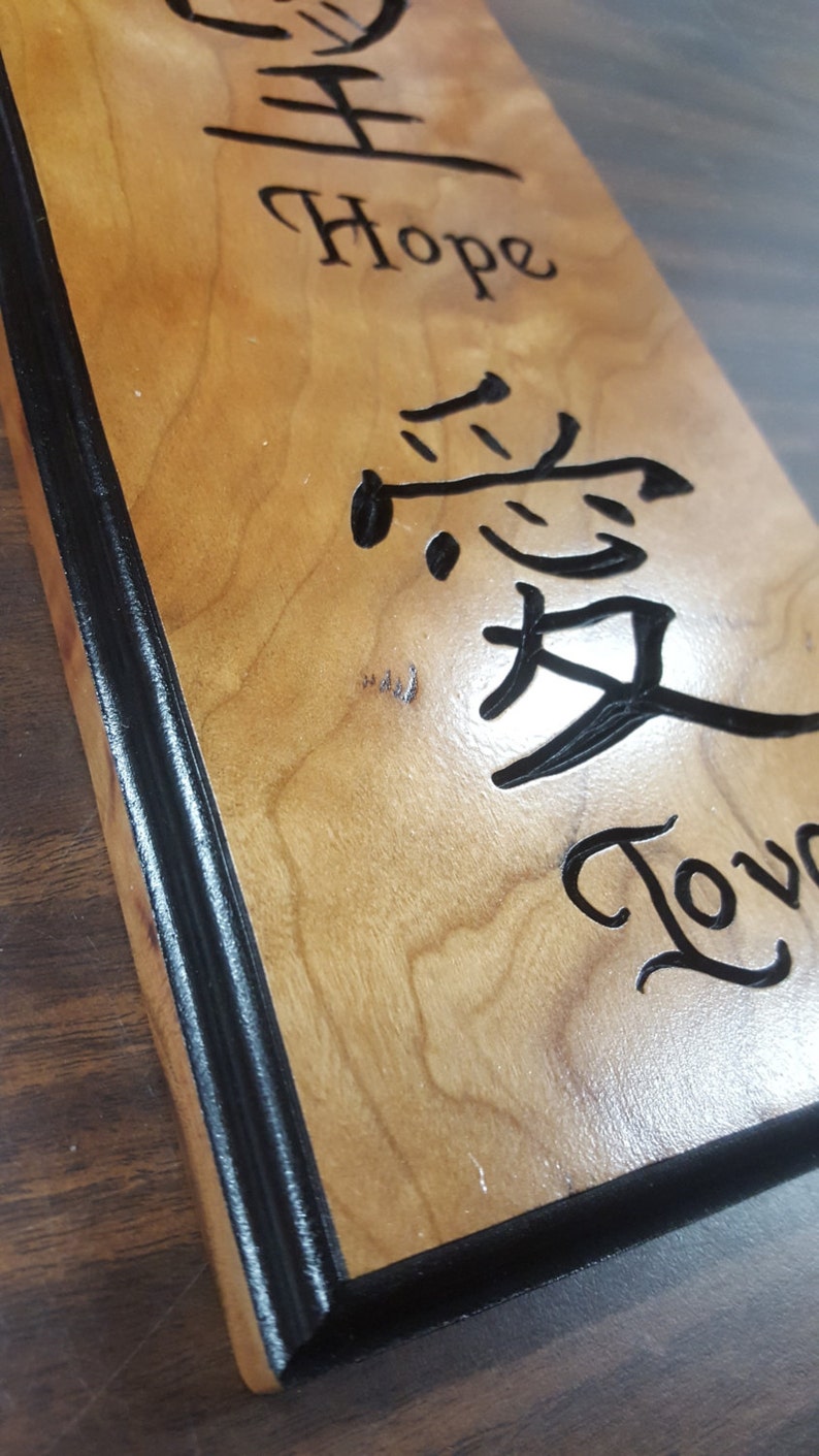 May include: A wooden sign with a black border. The sign has the words "Hope" and "Love" written in cursive. The word "Love" is written in Chinese characters.