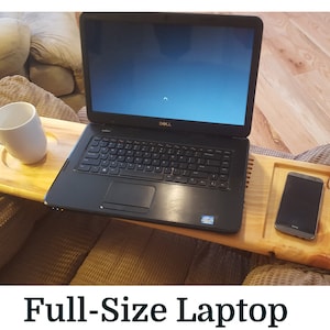Może przedstawiać: Drewniany stolik pod laptopa z wbudowanym uchwytem na kubek i miejscem na smartfon. Na stoliku znajduje się czarny laptop i biały kubek. Tekst "Full-Size Laptop" znajduje się na dole obrazu.