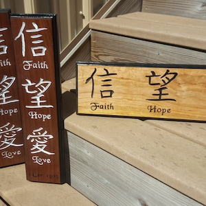 May include: Two wooden signs with black trim, each with three Chinese characters and their English translations: "Faith", "Hope", and "Love". The signs are on a wooden staircase.