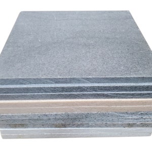 May include: A stack of gray, beige, and white acoustic soundproofing tiles. The tiles are made of a fibrous material and are designed to absorb sound.