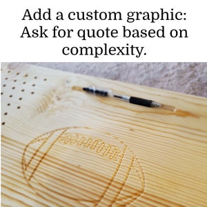 Może przedstawiać: Jasna drewniana deska z wygrawerowanym wzorem piłki nożnej. U g&oacute;ry znajduje się tekst "Add a custom graphic: Ask for quote based on complexity". Czarny długopis spoczywa w rowku na desce.