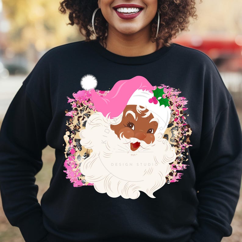 May include: Black Santa Claus with a pink hat and white beard on a black sweatshirt with a pink, white, and brown leopard print background. The text "DESIGN STUDIO" is visible on the sweatshirt.