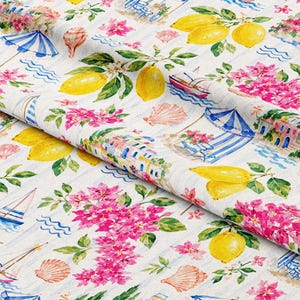 May include: White fabric with a watercolor design featuring yellow lemons, pink flowers, blue and white striped umbrellas, sailboats, and seashells. The pattern has a coastal theme.