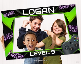 Może przedstawiać: Zielono-czarna rekwizyt do fotobudki z napisem "Gamer Zone" i "Level 9" w fioletowym neonowym tekście. Rekwizyt zawiera również imię "Logan" w białym tekście i grafikę czarno-zielonego kontrolera do gier.
