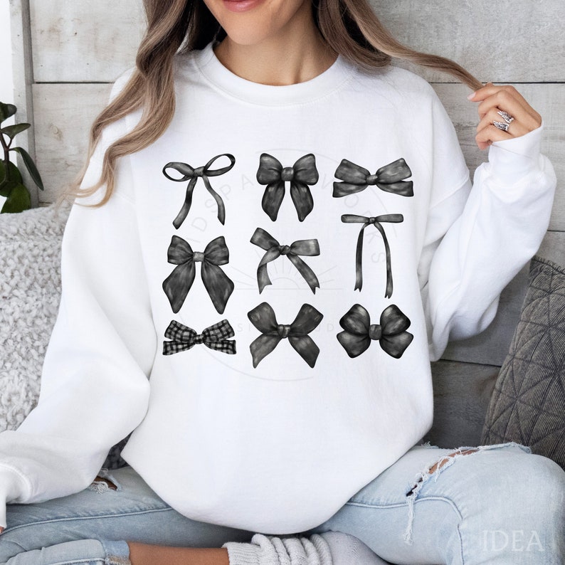 May include: A white sweatshirt with a design of nine black bows of different styles. The bows are arranged in three rows of three.