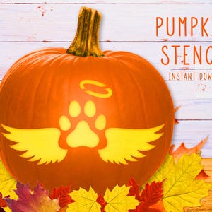 May include: A bright orange pumpkin featuring a carved yellow design of a paw print with wings and a halo above it. The text PUMPKIN STENCIL INSTANT DOWNLOAD is visible in the upper right corner. The pumpkin is surrounded by colorful autumn leaves.