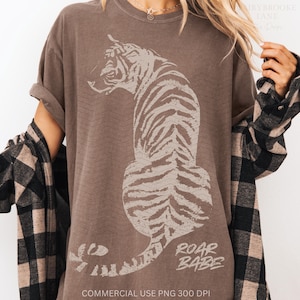 May include: A brown t-shirt with a white tiger graphic and the text "Roar Babe".