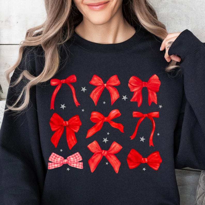 Puede incluir: Sudadera negra con un patr&oacute;n de lazos rojos. Los lazos est&aacute;n dispuestos en un patr&oacute;n de cuadr&iacute;cula con estrellas blancas entre ellos.