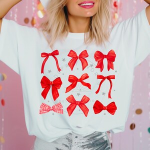 Puede incluir: Una camiseta blanca con un dise&ntilde;o de nueve lazos rojos en diferentes estilos. Los lazos est&aacute;n dispuestos en un c&iacute;rculo con una estrella en cada esquina.