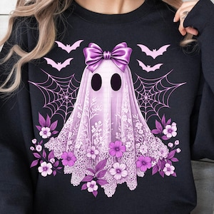 May include: Black sweatshirt featuring a lavender ghost design with a large bow, lace detailing, and floral accents. The design includes bats and spiderwebs, creating a spooky yet elegant Halloween theme.