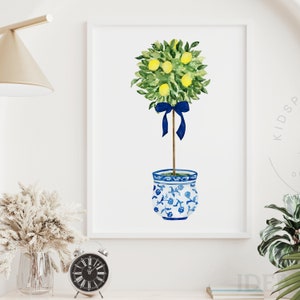 Pode incluir: Uma pintura em aquarela de uma &aacute;rvore de lim&atilde;o com uma fita azul amarrada ao redor do tronco. A &aacute;rvore est&aacute; plantada em um vaso de cer&acirc;mica azul e branco com um design floral.