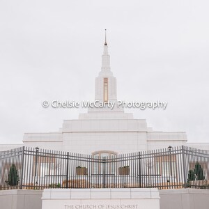May include: A white temple with a tall spire, set against a cloudy sky. The building has a symmetrical design with multiple levels and a fence in front. The text on the building reads "THE CHURCH OF JESUS CHRIST OF LATTER-DAY SAINTS FARMINGTON NEW MEXICO TEMPLE."