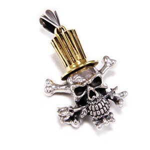 May include: A silver skull pendant with a gold top hat and a rose in its mouth. The skull is surrounded by crossed bones.