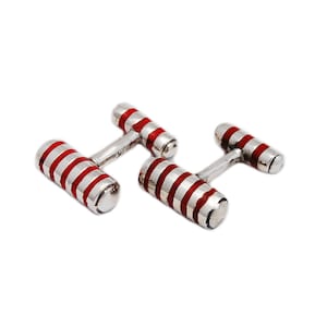 May include: A pair of silver cufflinks with red and white striped enamel.