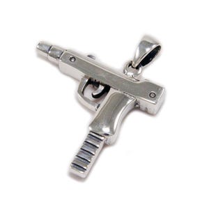May include: A silver-colored pendant in the shape of a submachine gun. The pendant has a detailed design, including the trigger, magazine, and barrel. The pendant is suspended from a small loop at the top.