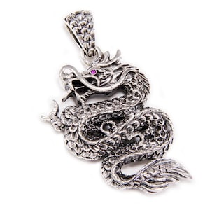 Puede incluir: Colgante de plata con forma de dragón con un ojo de piedra preciosa rosa. El dragón está enroscado y tiene escamas detalladas.